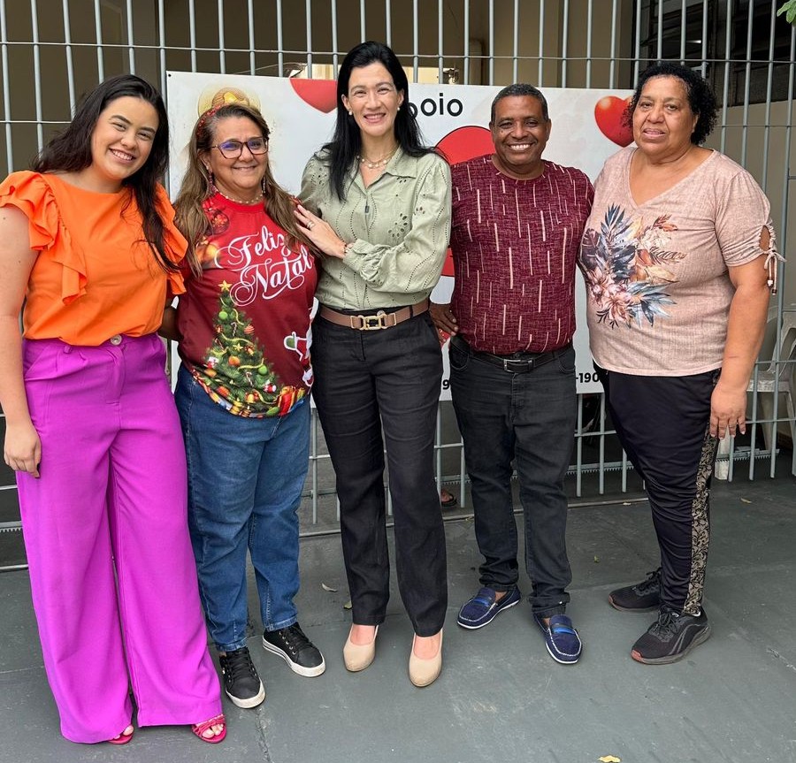 Voluntária segurando as mãos de uma senhora acolhida na sala de convivência da casa